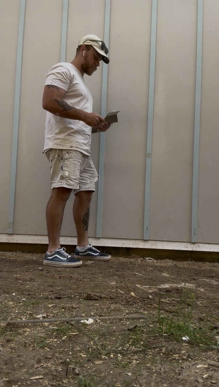Harts painter checking exterior cladding before painting