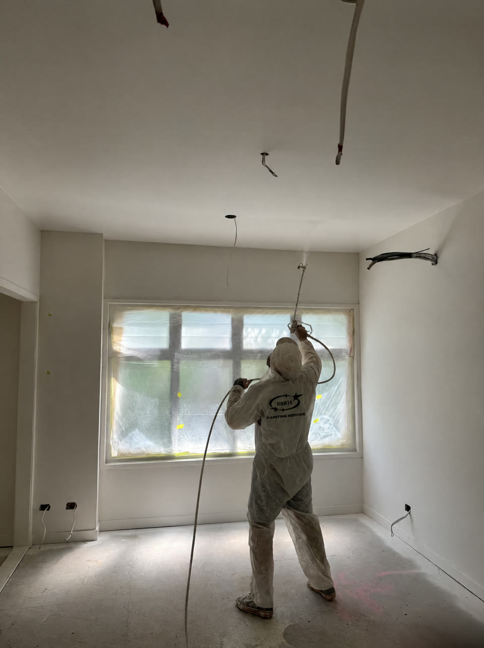 Harts painter spraying a ceiling with windows masked off