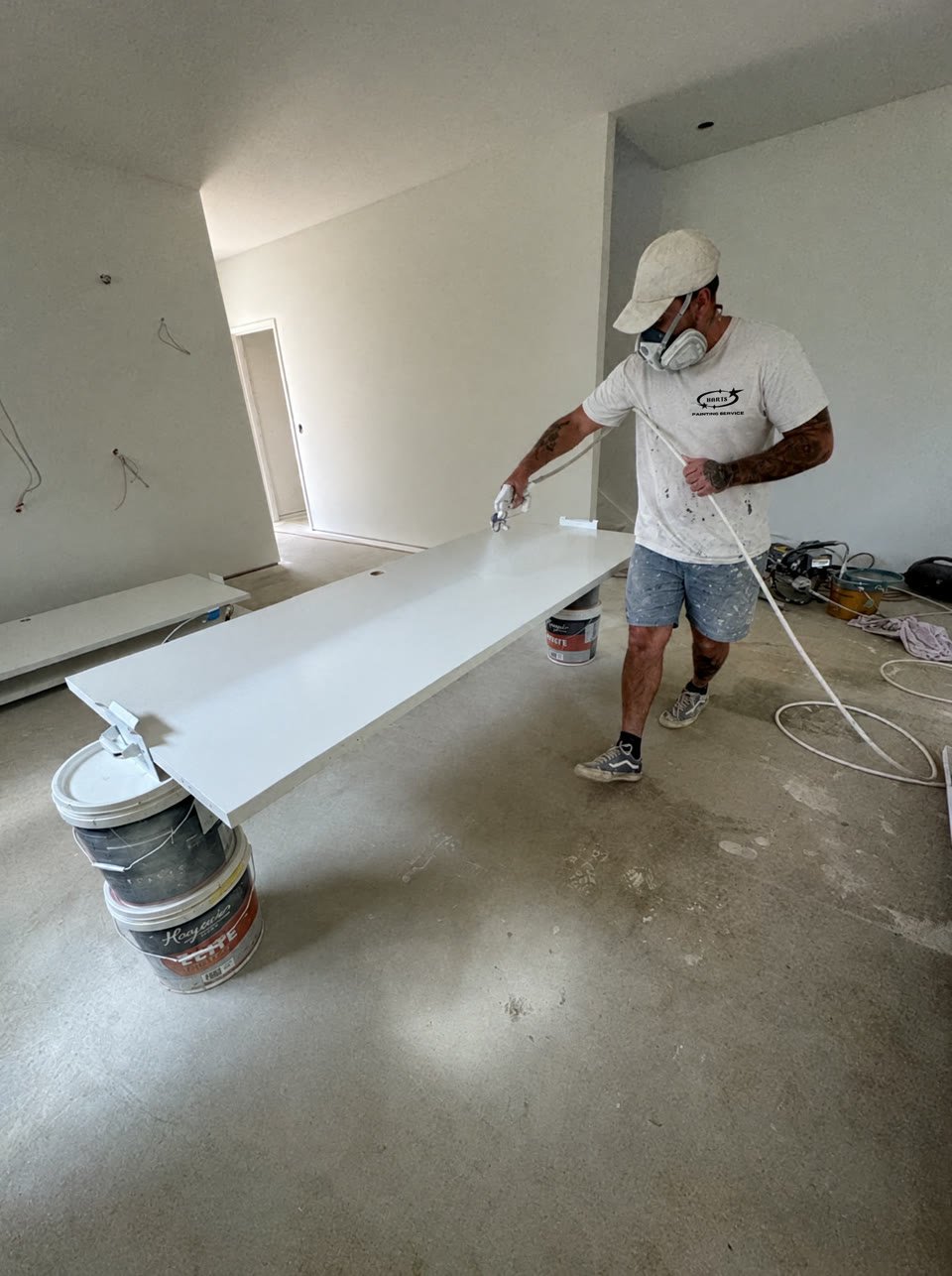 Harts painter spray-finishing shelving inside a new home